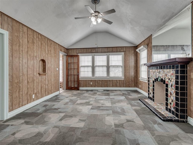 2617 NW 23rd St, Oklahoma City, OK 73107 - unfurnished living room featuring ceiling fan, wood walls, baseboards, healthy amount of natural light, and vaulted ceiling