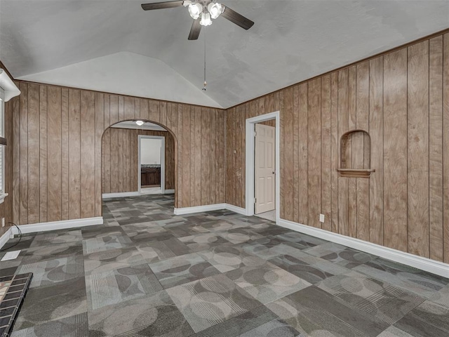 2617 NW 23rd St, Oklahoma City, OK 73107 - spare room with arched walkways, ceiling fan, carpet floors, vaulted ceiling, and wood walls