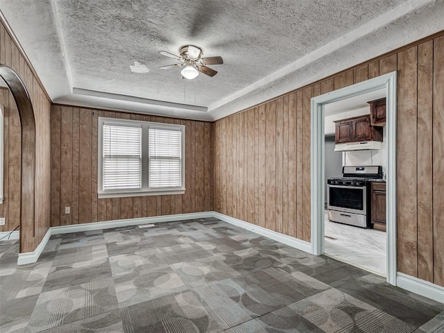2617 NW 23rd St, Oklahoma City, OK 73107 - carpeted spare room with ceiling fan, a textured ceiling, wood walls, and baseboards