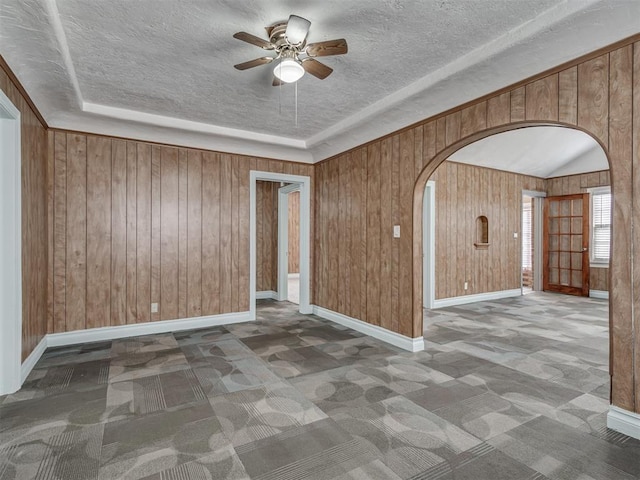 2617 NW 23rd St, Oklahoma City, OK 73107 - unfurnished room featuring arched walkways, a ceiling fan, carpet floors, a textured ceiling, and wooden walls