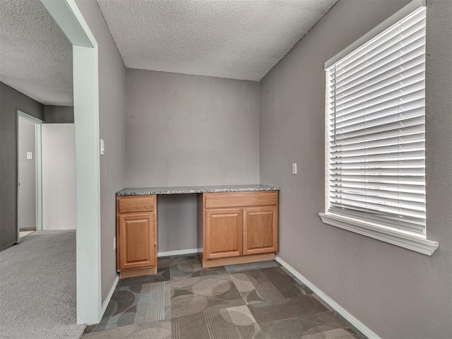 2617 NW 23rd St, Oklahoma City, OK 73107 - kitchen featuring carpet flooring, a textured ceiling, an office area, and baseboards