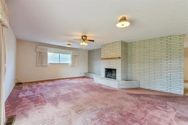 1009 Cherokee Pl, Lindsay, OK 73052 - unfurnished living room featuring ceiling fan, carpet flooring, a brick fireplace, brick wall, and baseboards