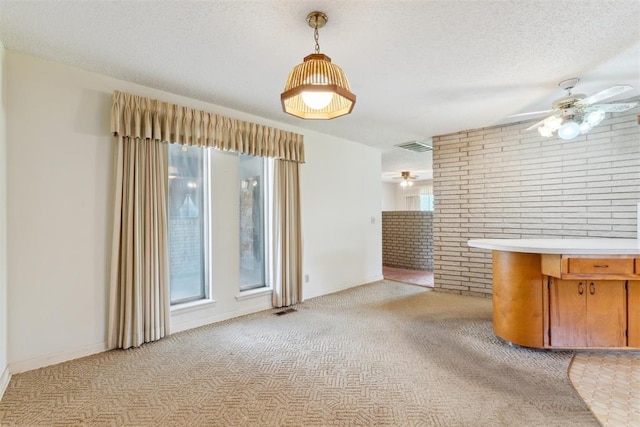 1009 Cherokee Pl, Lindsay, OK 73052 - unfurnished living room with ceiling fan, light colored carpet, brick wall, and a textured ceiling
