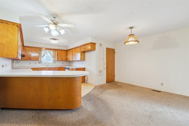 1009 Cherokee Pl, Lindsay, OK 73052 - kitchen with light countertops, a peninsula, light carpet, brown cabinetry, and a ceiling fan