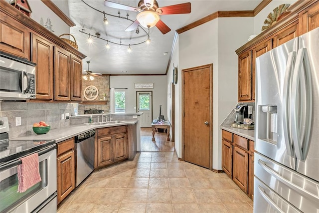 8701 Long Spur Trl, Edmond, OK 73034 - kitchen with appliances with stainless steel finishes, ceiling fan, a sink, ornamental molding, and brown cabinetry