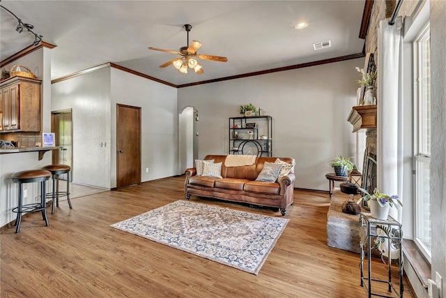 8701 Long Spur Trl, Edmond, OK 73034 - living area featuring arched walkways, ornamental molding, ceiling fan, light wood finished floors, and a fireplace