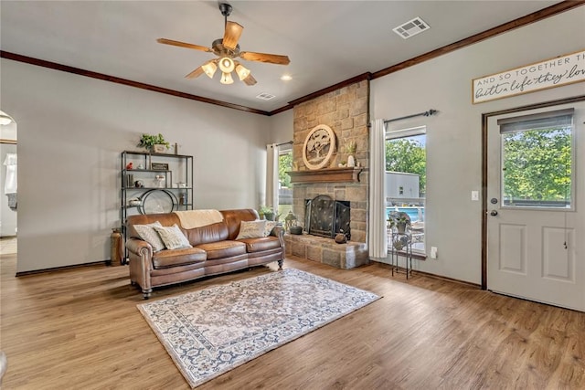 8701 Long Spur Trl, Edmond, OK 73034 - living room featuring ornamental molding, a ceiling fan, a stone fireplace, wood finished floors, and baseboards
