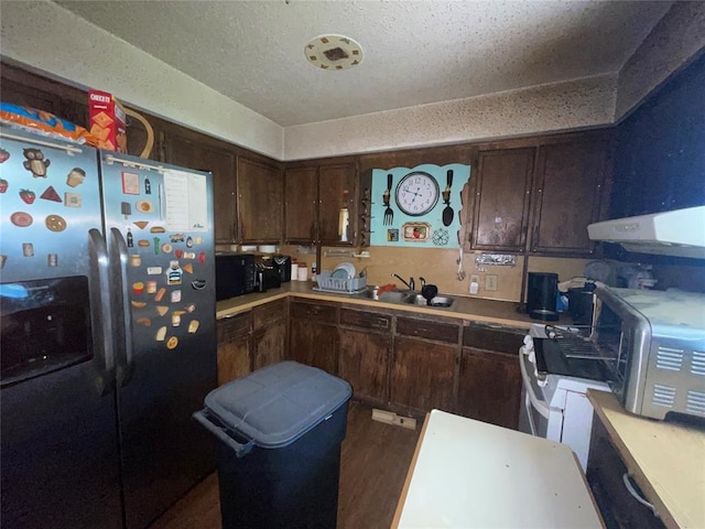 811 N Admire Ave, El Reno, OK 73036 - kitchen with stainless steel fridge with ice dispenser, under cabinet range hood, dark brown cabinetry, dark wood-type flooring, and a sink