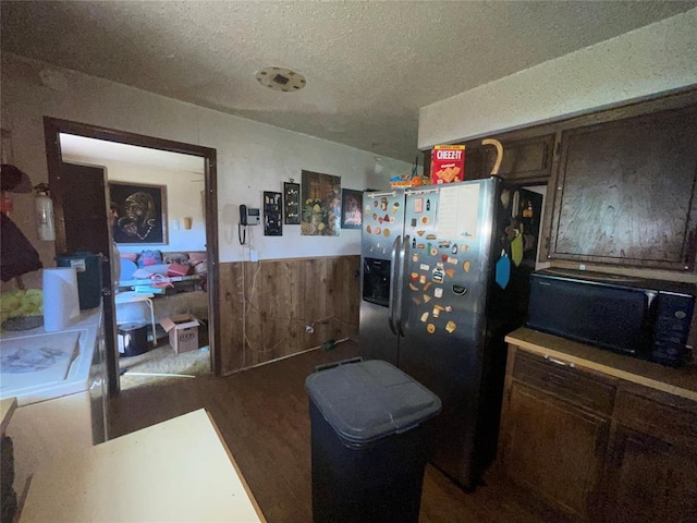 811 N Admire Ave, El Reno, OK 73036 - kitchen featuring black microwave, wood finished floors, a textured ceiling, a wainscoted wall, and stainless steel fridge with ice dispenser