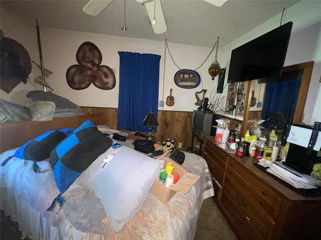 811 N Admire Ave, El Reno, OK 73036 - bedroom featuring wainscoting, wood walls, a ceiling fan, and a textured ceiling