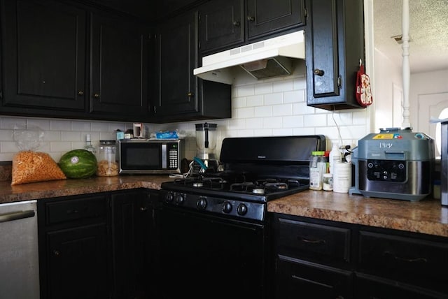 4753 SE 17th St, Oklahoma City, OK 73115 - kitchen featuring under cabinet range hood, stainless steel appliances, dark cabinets, backsplash, and a textured ceiling