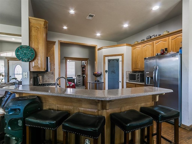 9315 Fendrych Dr, Oklahoma City, OK 73165 - kitchen featuring appliances with stainless steel finishes, a peninsula, backsplash, plenty of natural light, and recessed lighting