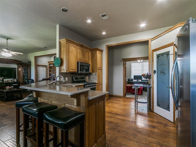 9315 Fendrych Dr, Oklahoma City, OK 73165 - kitchen featuring stainless steel appliances, a peninsula, a sink, a breakfast bar, and dark wood-style floors