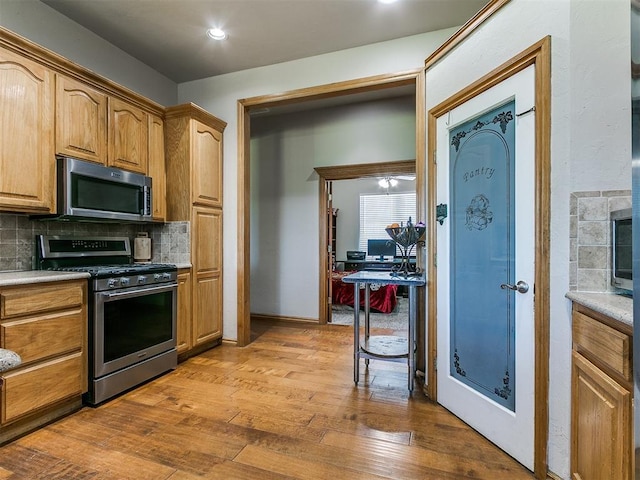 9315 Fendrych Dr, Oklahoma City, OK 73165 - kitchen with appliances with stainless steel finishes, decorative backsplash, wood-type flooring, light countertops, and baseboards