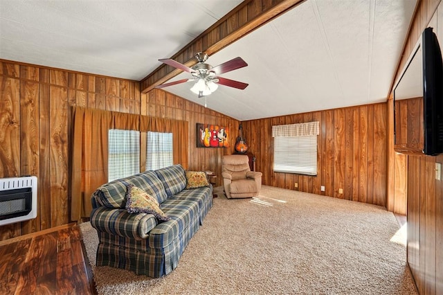 carpeted living area with wood walls, healthy amount of natural light, a ceiling fan, and heating unit