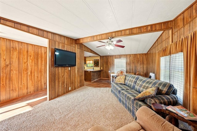 living room featuring wood walls, lofted ceiling, a ceiling fan, and carpet floors
