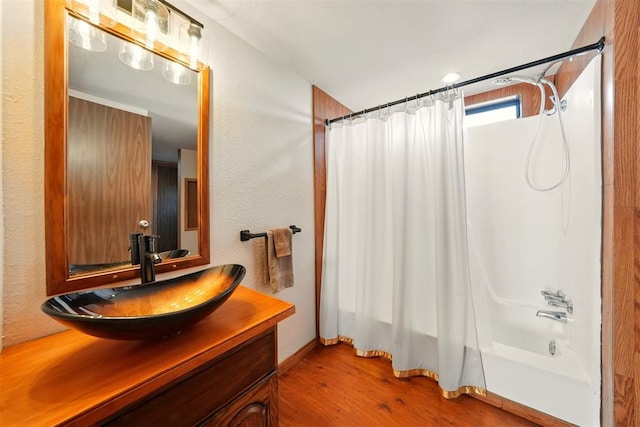full bath featuring wood finished floors, shower / bath combination with curtain, vanity, and baseboards