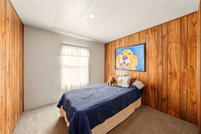 carpeted bedroom featuring wood walls and a textured ceiling