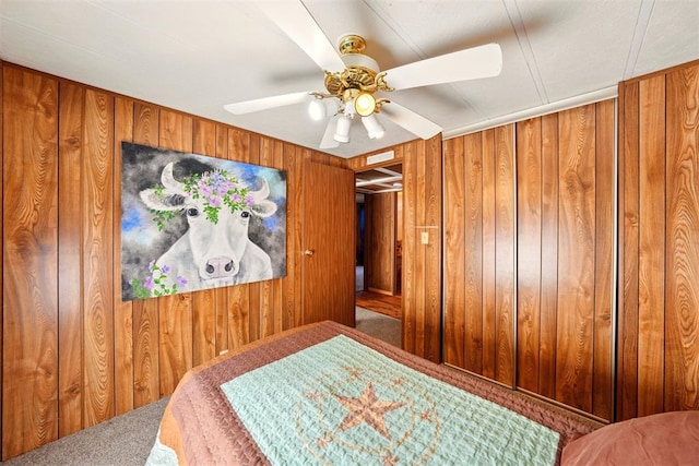 carpeted bedroom featuring wooden walls and ceiling fan