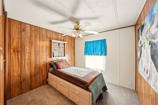 bedroom featuring carpet floors, wooden walls, a textured ceiling, and a ceiling fan