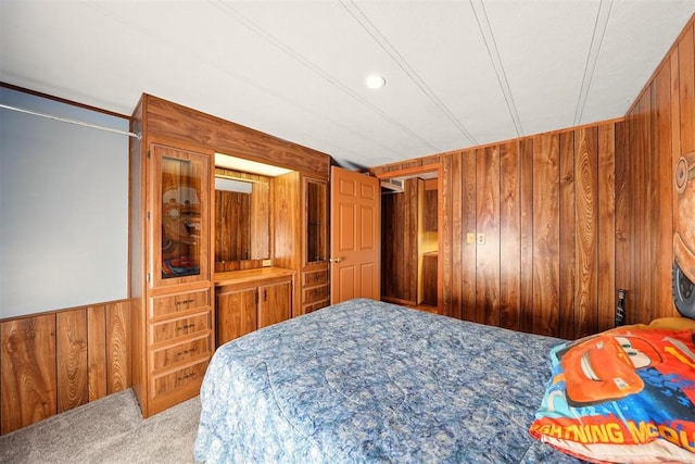 carpeted bedroom with wood walls and recessed lighting
