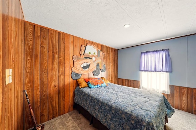 carpeted bedroom featuring wooden walls, a textured ceiling, and wainscoting