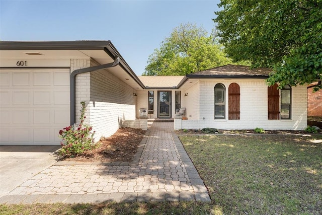 view of front facade featuring brick siding, a garage, and a front lawn