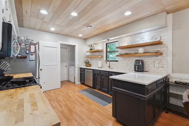 kitchen featuring a sink, open shelves, stainless steel appliances, light wood-style floors, and decorative backsplash