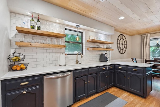 kitchen featuring stainless steel dishwasher, a sink, open shelves, light wood-style floors, and a peninsula