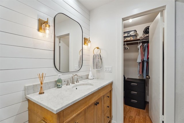 bathroom featuring wood finished floors, a walk in closet, and vanity
