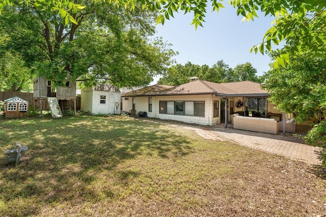 rear view of property featuring a storage unit, an outdoor structure, and a patio