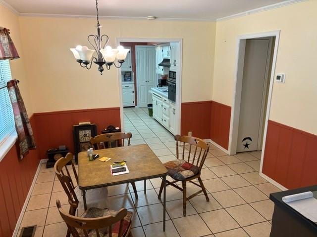 405 W Choctaw St, Lindsay, OK 73052 - dining area with a wainscoted wall, ornamental molding, a chandelier, light tile patterned floors, and wood walls