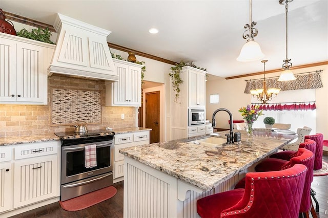 kitchen with appliances with stainless steel finishes, a sink, custom exhaust hood, ornamental molding, and a chandelier