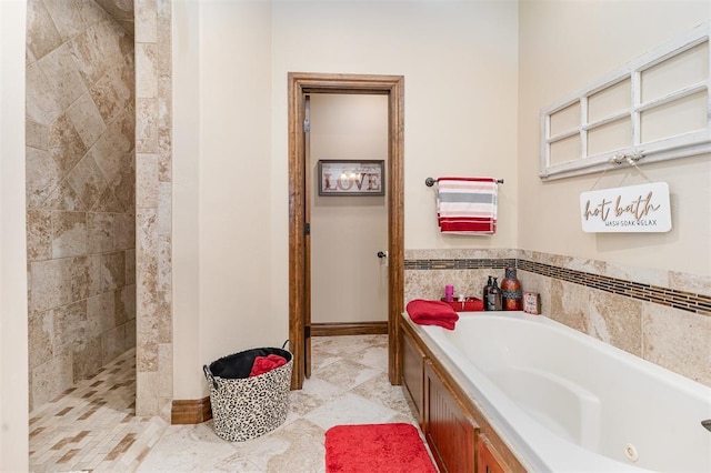 bathroom featuring a whirlpool tub, a tile shower, and baseboards