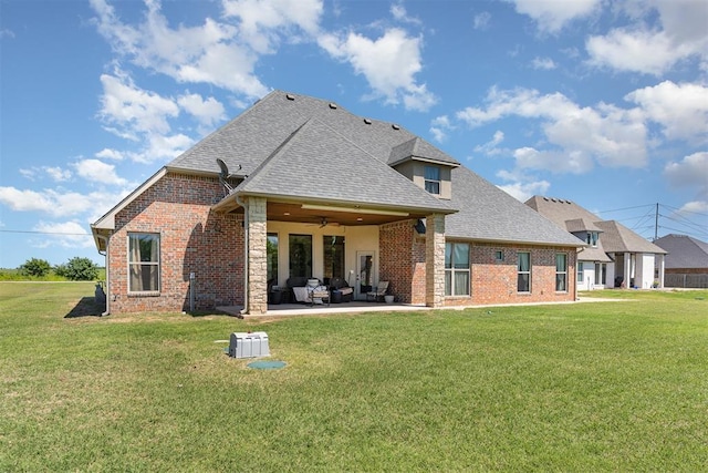 rear view of property featuring ceiling fan, a patio, roof with shingles, a yard, and brick siding
