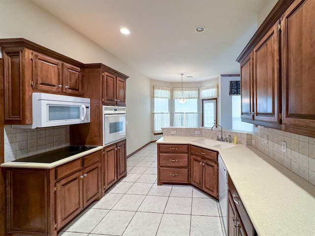 3424 Teton Ct, Norman, OK 73072 - kitchen with white appliances, decorative backsplash, a peninsula, light countertops, and light tile patterned floors