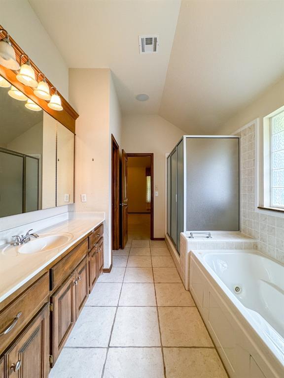 3424 Teton Ct, Norman, OK 73072 - full bath featuring vanity, a whirlpool tub, a shower stall, tile patterned flooring, and vaulted ceiling