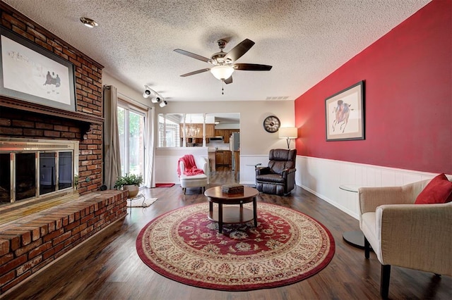 5708 NW 87th St, Oklahoma City, OK 73132 - living area featuring a textured ceiling, wainscoting, wood finished floors, a ceiling fan, and a fireplace