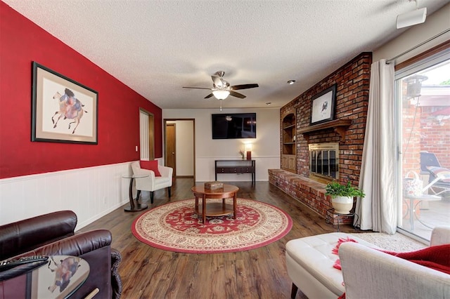 5708 NW 87th St, Oklahoma City, OK 73132 - living room with a textured ceiling, wood finished floors, ceiling fan, a fireplace, and a wainscoted wall