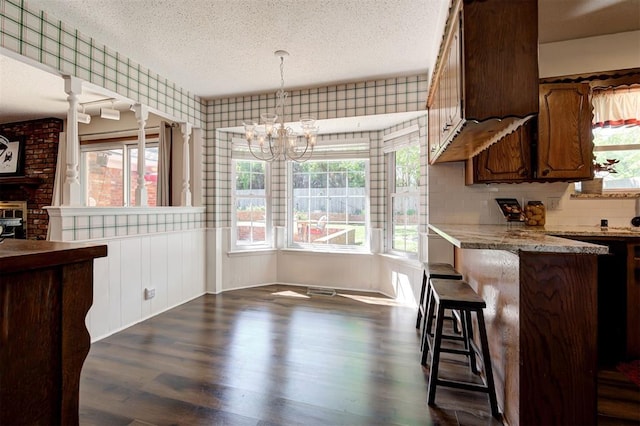 5708 NW 87th St, Oklahoma City, OK 73132 - kitchen featuring a textured ceiling, a chandelier, healthy amount of natural light, dark wood-style floors, and a kitchen breakfast bar