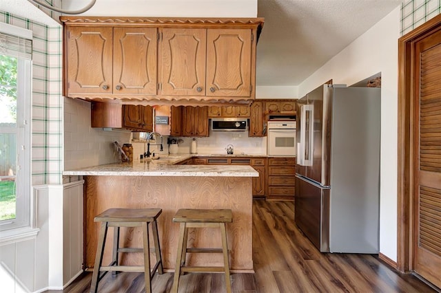 5708 NW 87th St, Oklahoma City, OK 73132 - kitchen featuring stainless steel appliances, a peninsula, a sink, dark wood-style floors, and backsplash