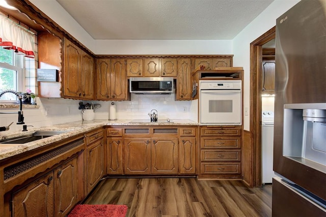 5708 NW 87th St, Oklahoma City, OK 73132 - kitchen with appliances with stainless steel finishes, a sink, dark wood-style flooring, brown cabinets, and a textured ceiling