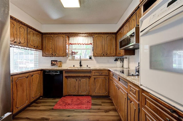 5708 NW 87th St, Oklahoma City, OK 73132 - kitchen with black appliances, a sink, dark wood finished floors, brown cabinets, and a textured ceiling