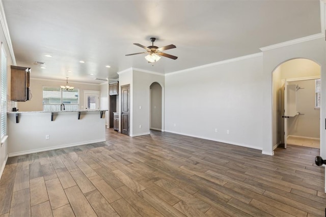8345 NW 137th St, Oklahoma City, OK 73142 - unfurnished living room with arched walkways, a ceiling fan, dark wood-style floors, baseboards, and crown molding