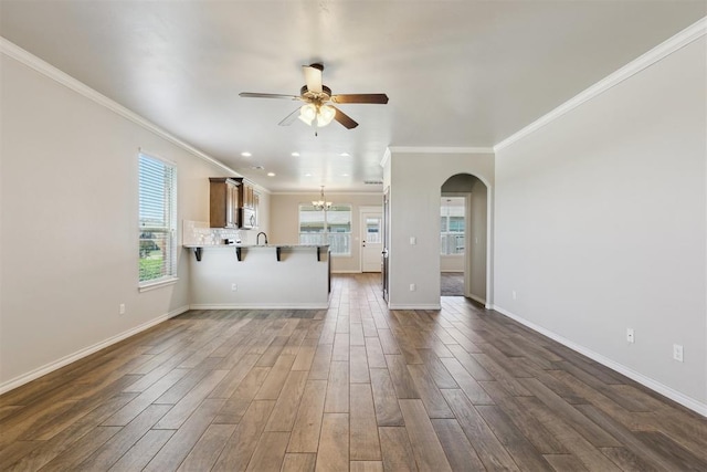 8345 NW 137th St, Oklahoma City, OK 73142 - unfurnished living room featuring ceiling fan, crown molding, arched walkways, dark wood-style floors, and baseboards