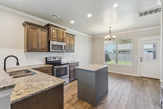 8345 NW 137th St, Oklahoma City, OK 73142 - kitchen with stainless steel appliances, a sink, a chandelier, light stone countertops, and ornamental molding
