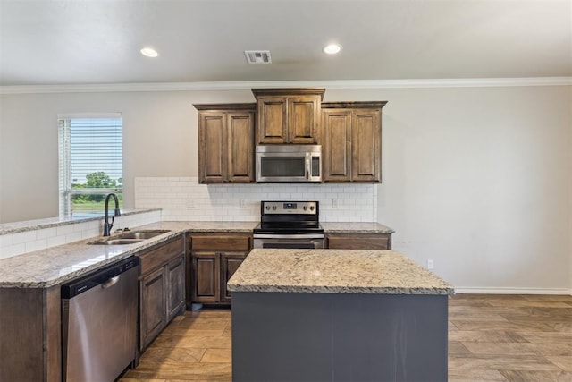 8345 NW 137th St, Oklahoma City, OK 73142 - kitchen featuring stainless steel appliances, a sink, crown molding, light stone counters, and decorative backsplash