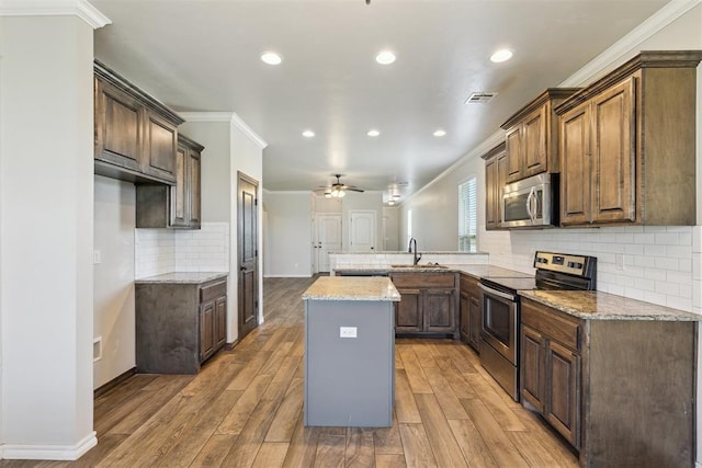 8345 NW 137th St, Oklahoma City, OK 73142 - kitchen with appliances with stainless steel finishes, a peninsula, a sink, ornamental molding, and tasteful backsplash