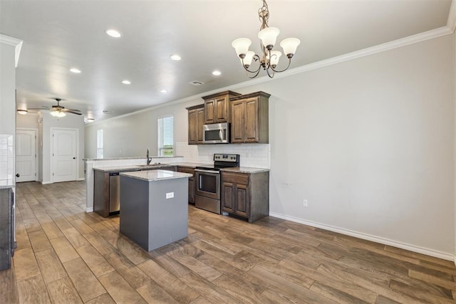 8345 NW 137th St, Oklahoma City, OK 73142 - kitchen featuring appliances with stainless steel finishes, a sink, a peninsula, ornamental molding, and a kitchen island