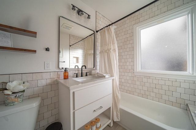 1017 Dean Pl, Oklahoma City, OK 73117 - bathroom featuring tile walls, toilet, vanity, and shower / bath combo with shower curtain